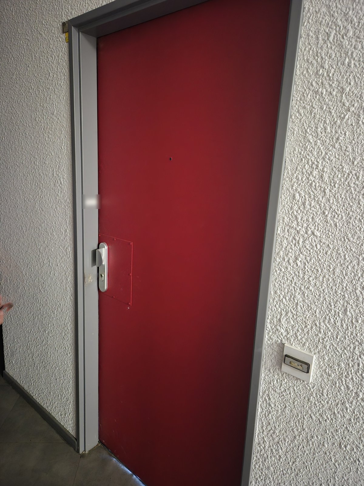 Porte d'entrée d'appartement avant blindage, vue du palier, avec plaque de réparation autour de la serrure