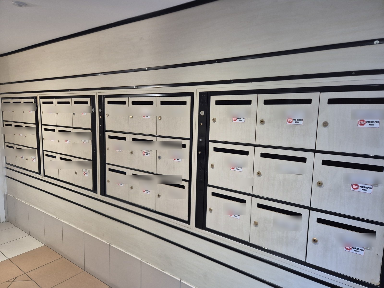 Anciens blocs de boîtes aux lettres vétustes dans le hall d'une résidence, avant remplacement